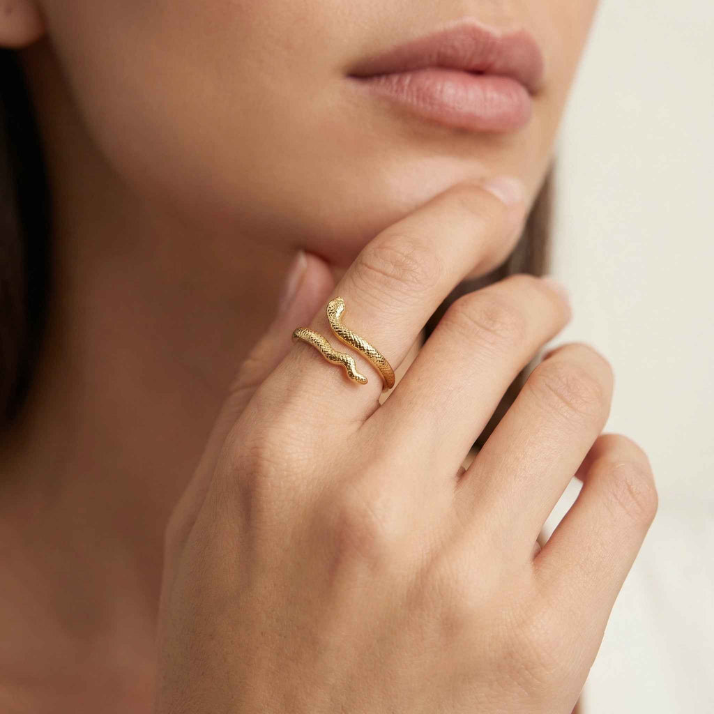 Close-up of a hand wearing a gold ring with a neutral background